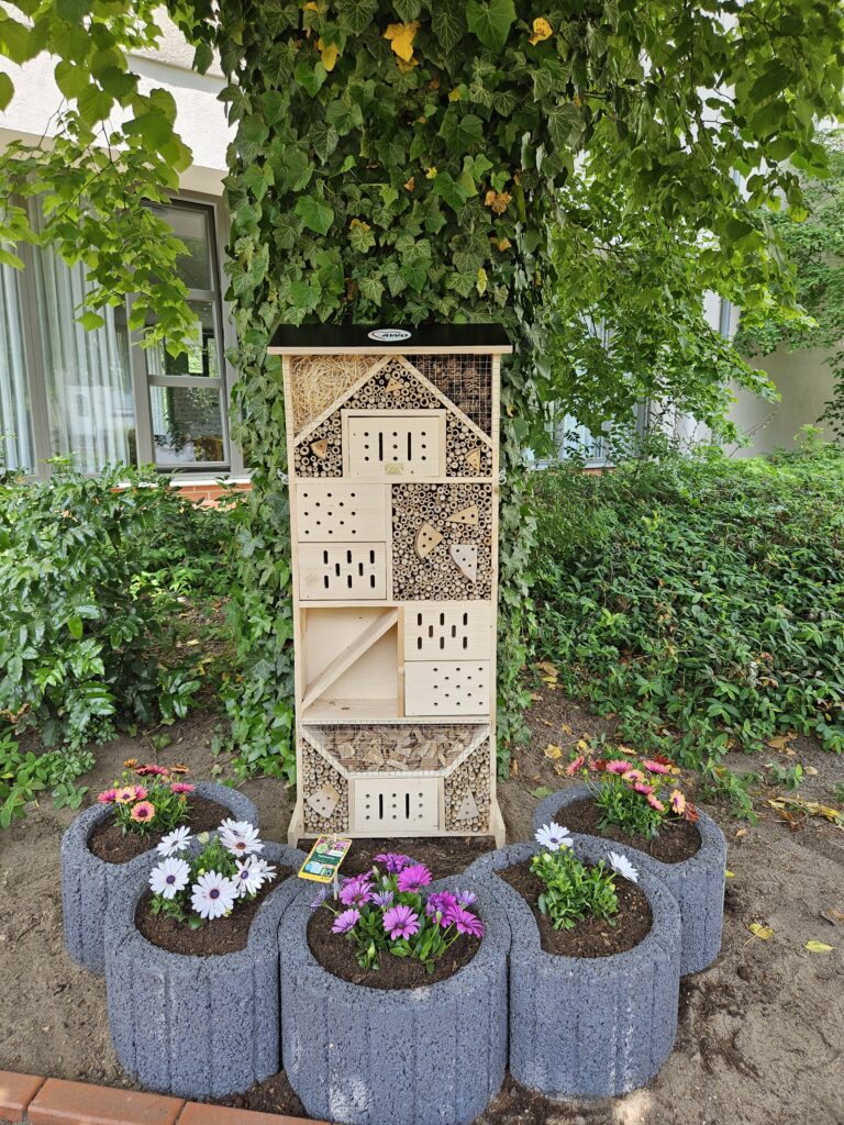 Anblick des Insektenhotels, umringt von Blumenbeeten